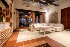 Un amplio salón con un sofá blanco, una mesita de centro y una pared decorada con ladrillo.
