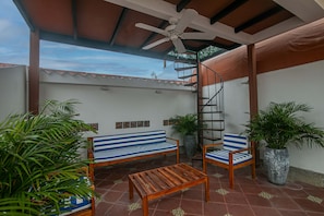 A covered patio area with a ceiling fan, a wooden bench, a striped sofa, a chair, and potted plants. - Luxury 5 Bdrm Villa Walled City (Cartagena de Indias)