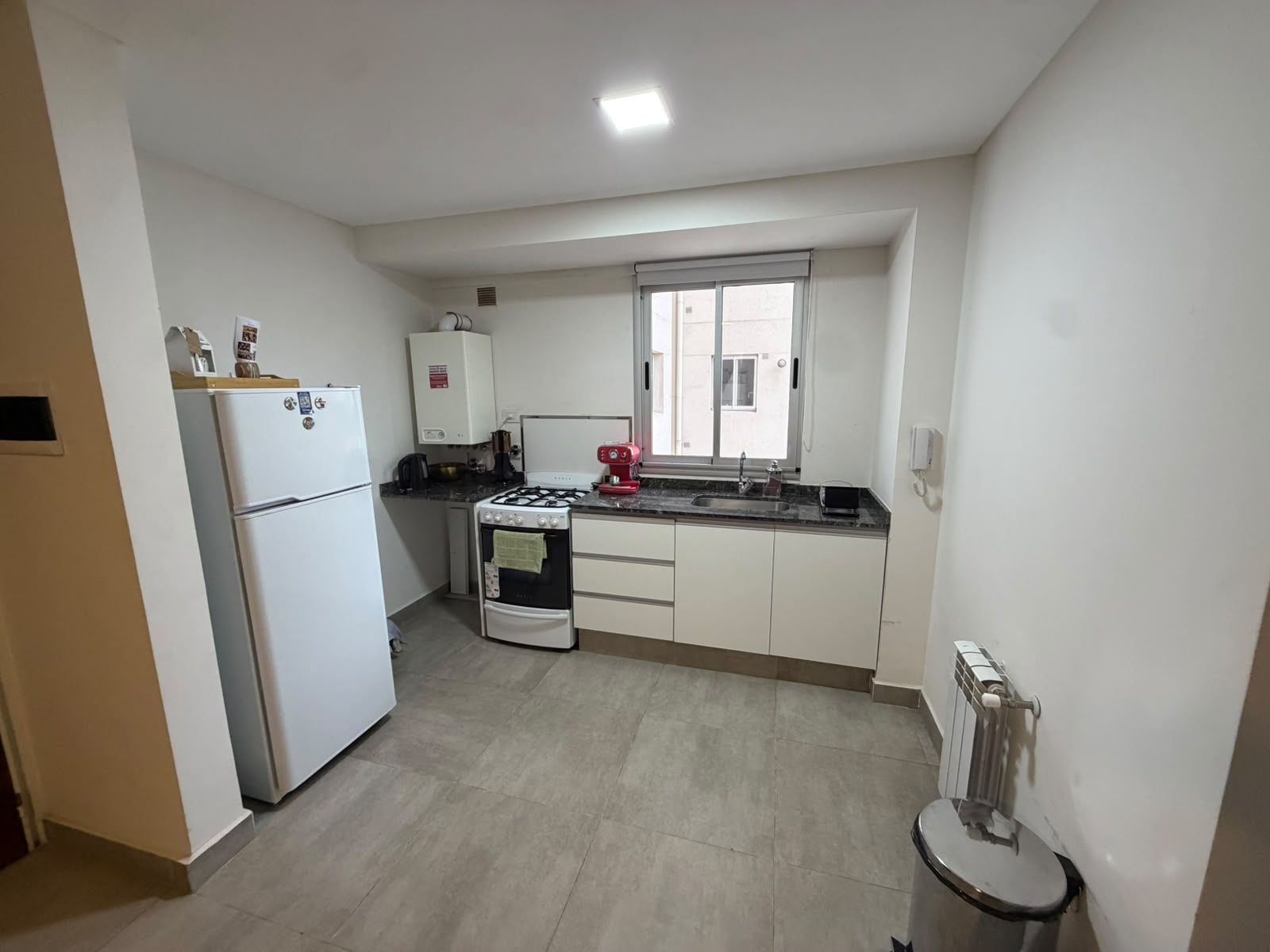 Una cocina compacta con refrigerador, estufa y lavadero.