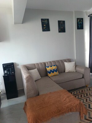 A living room with a sofa, a coffee machine, and a patterned rug. - Arc II Residence, Wangige  Modern 1-Bedroom with Pool & Gym (Wangige)