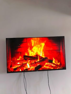 A television displaying a fireplace with logs and flames. - Arc II Residence, Wangige  Modern 1-Bedroom with Pool & Gym (Wangige)