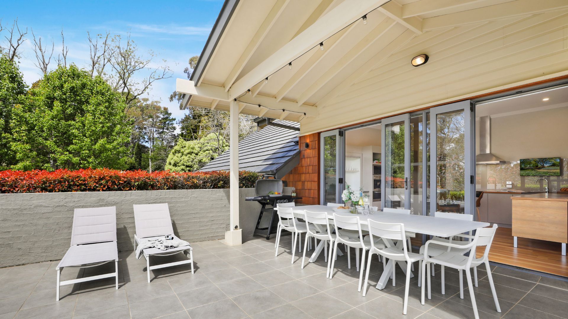 Un patio exterior con una mesa de comedor y sillas, una parrilla y una zona de estar con sillones.