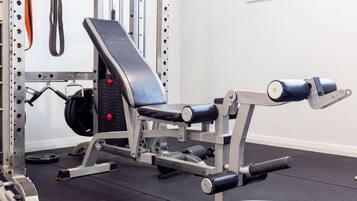 Een sportschool met een bankdrukapparaat, gewichtstapel en diverse fitnessapparaten.