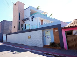A modern two-story building with a white facade, a balcony, and a sign for 'Praia Studios.' - Cozy 1-bedroom studio with living room, kitchen, AC in Ponta da Fruta Vila Velha (Vila Velha)