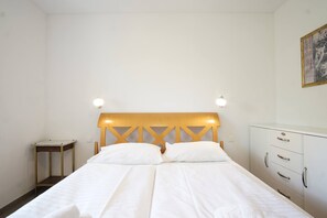 Un lit simple avec une tête de lit en bois et deux tables de chevet, dont une avec une lampe.