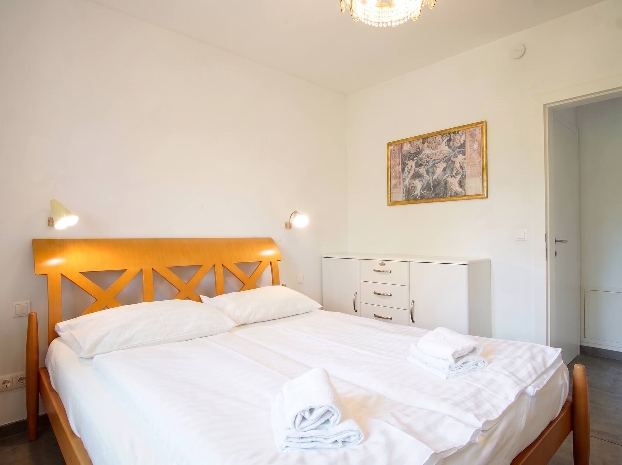 Une chambre d’hôtel avec un lit, des lampes de chevet, une armoire et un tableau au mur.