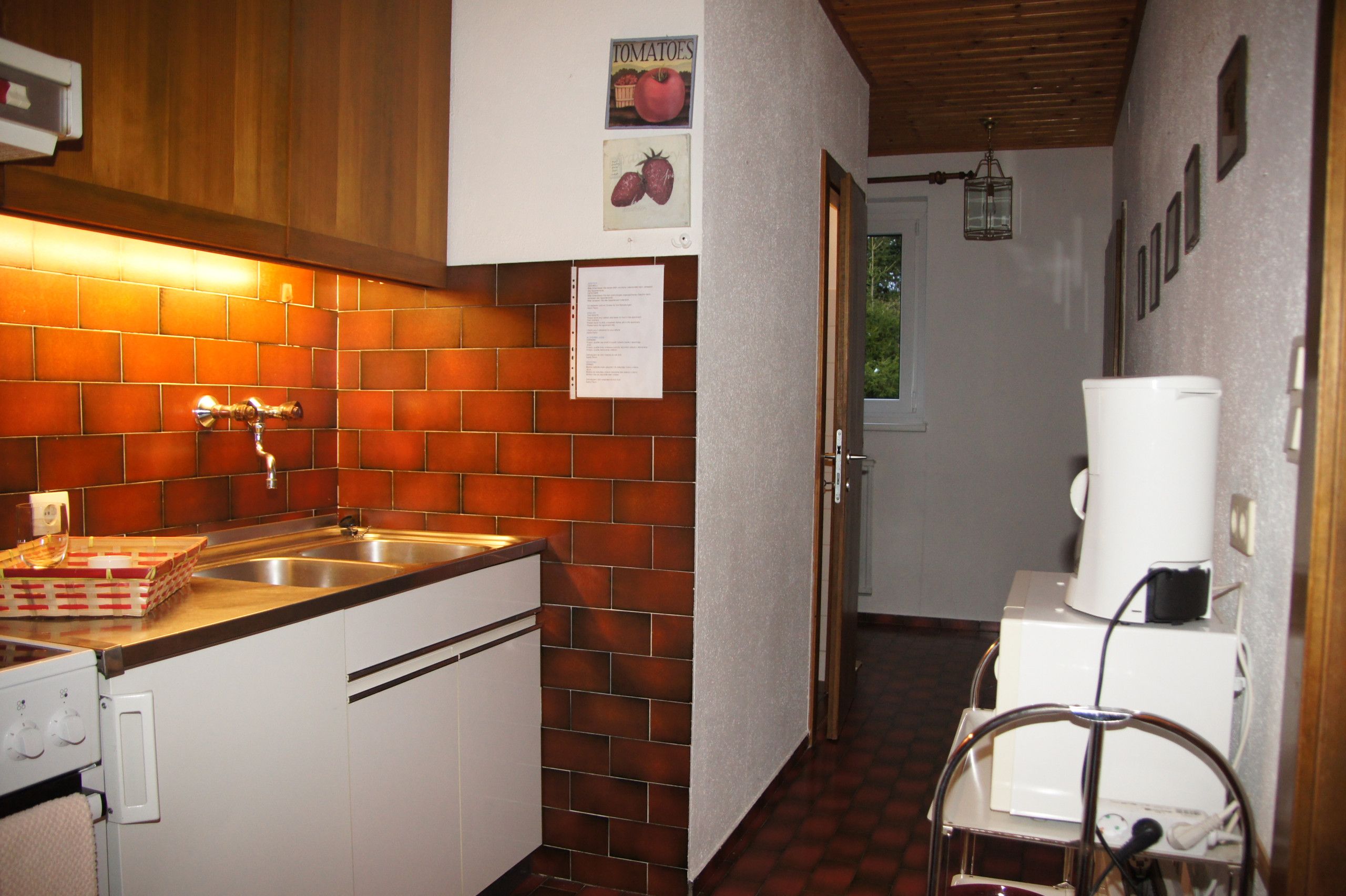 Eine Küche mit Ziegelrückwand, Spüle aus Edelstahl und einem weißen Kühlschrank.