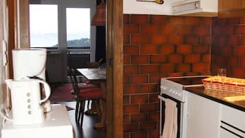 Eine Küche mit Backsteinwand, einem Herd, einem Spülbecken und einem Essbereich mit Blick.