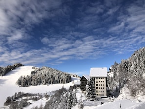 Un paisaje montañoso cubierto de nieve con una cabaña y un edificio con amplias ventanas.