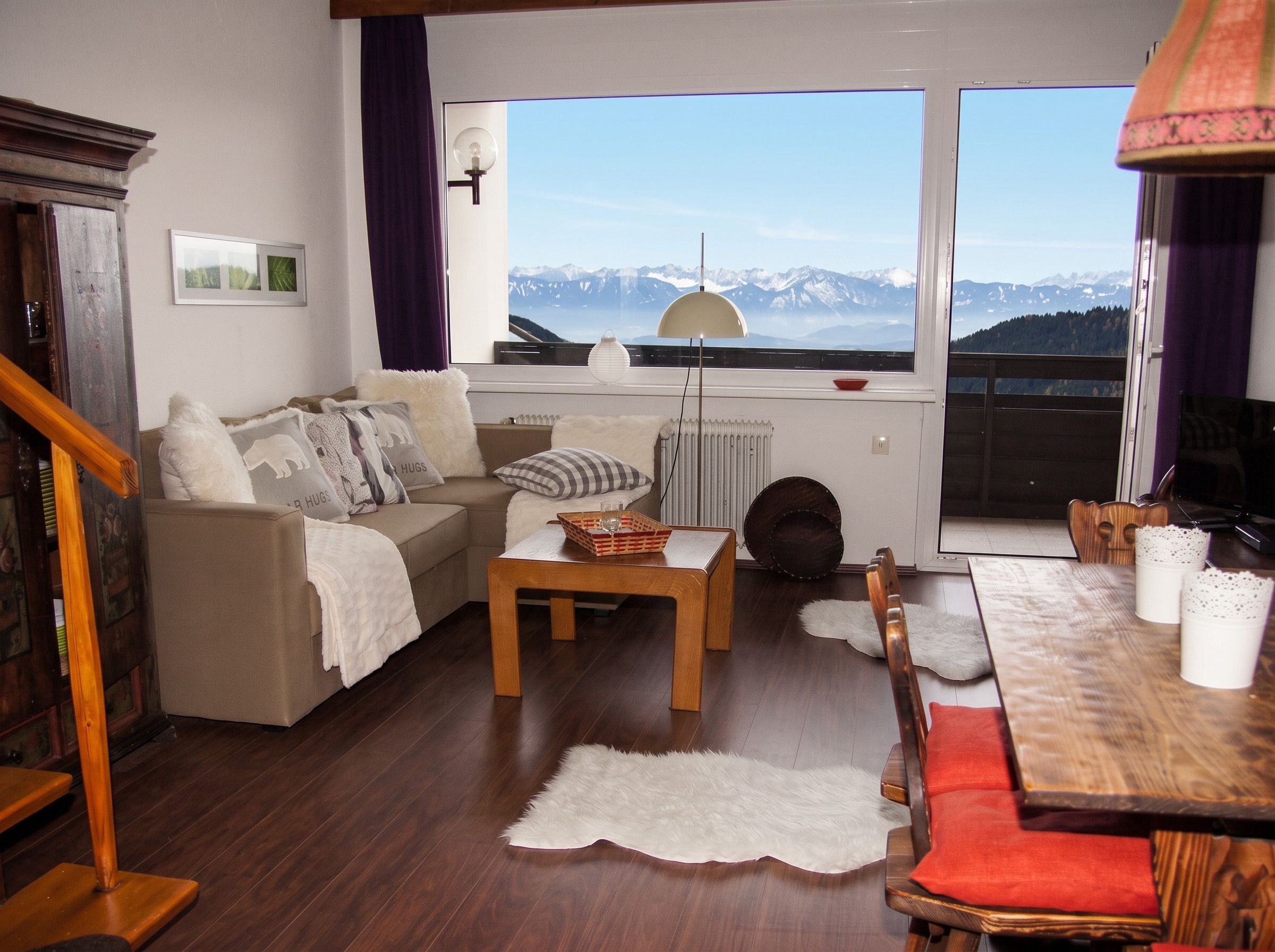 Una sala de estar acogedora con un sofá, una mesa de centro y vistas a montañas a través de amplios ventanales.