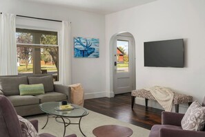 A living room with a sofa, coffee table, and a television on the wall. - The Downtown Cottage (Driggs)