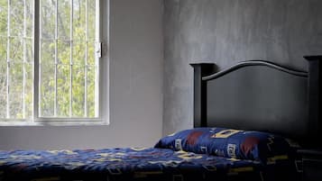A room with a bed, a window, and a plain wall.