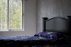 Una habitación con cama, ventana y pared lisa.