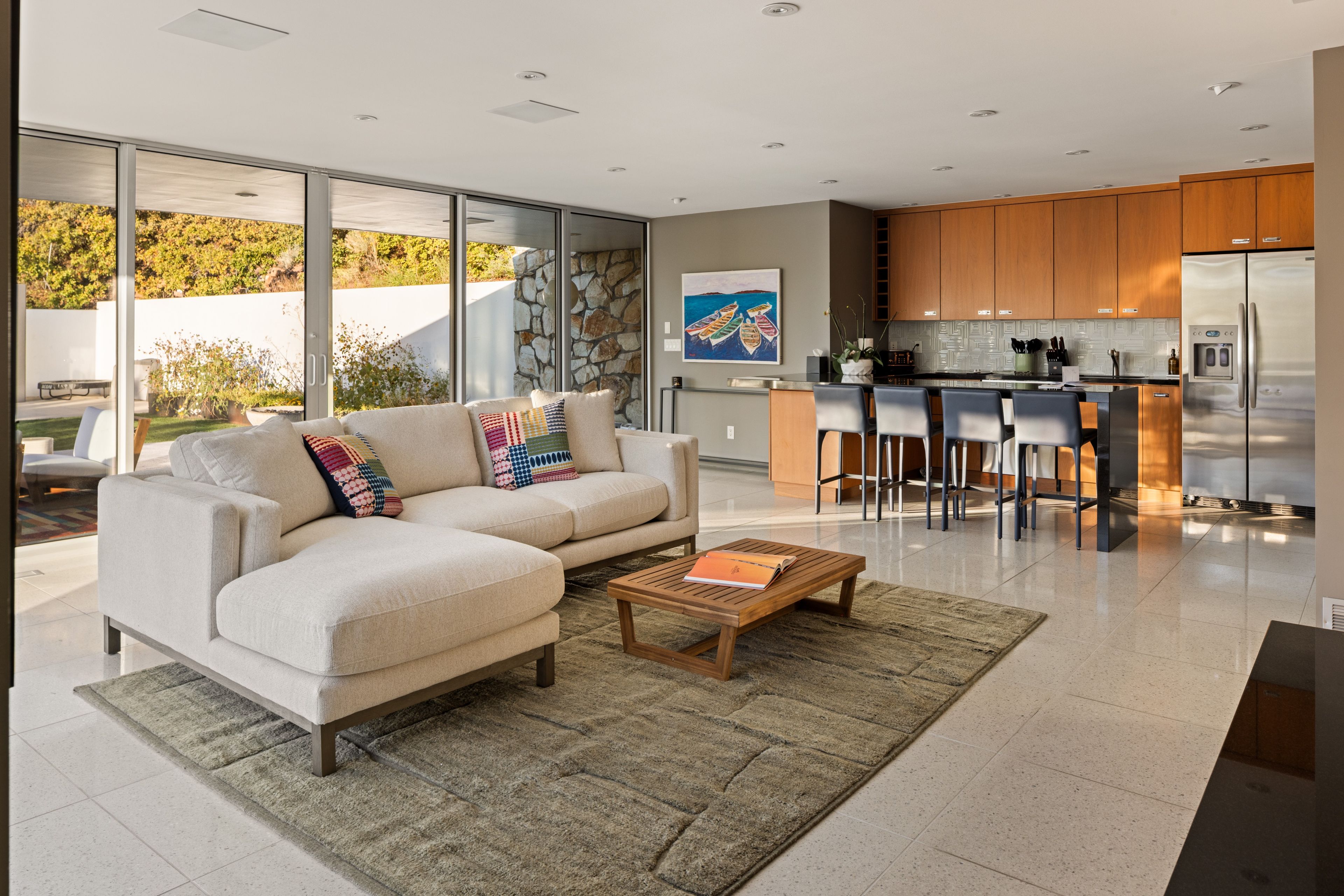 A modern kitchen with a large island, bar stools, and a refrigerator.