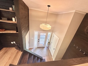Un escalier menant à un palier avec une porte, un luminaire suspendu et un mur en bois.