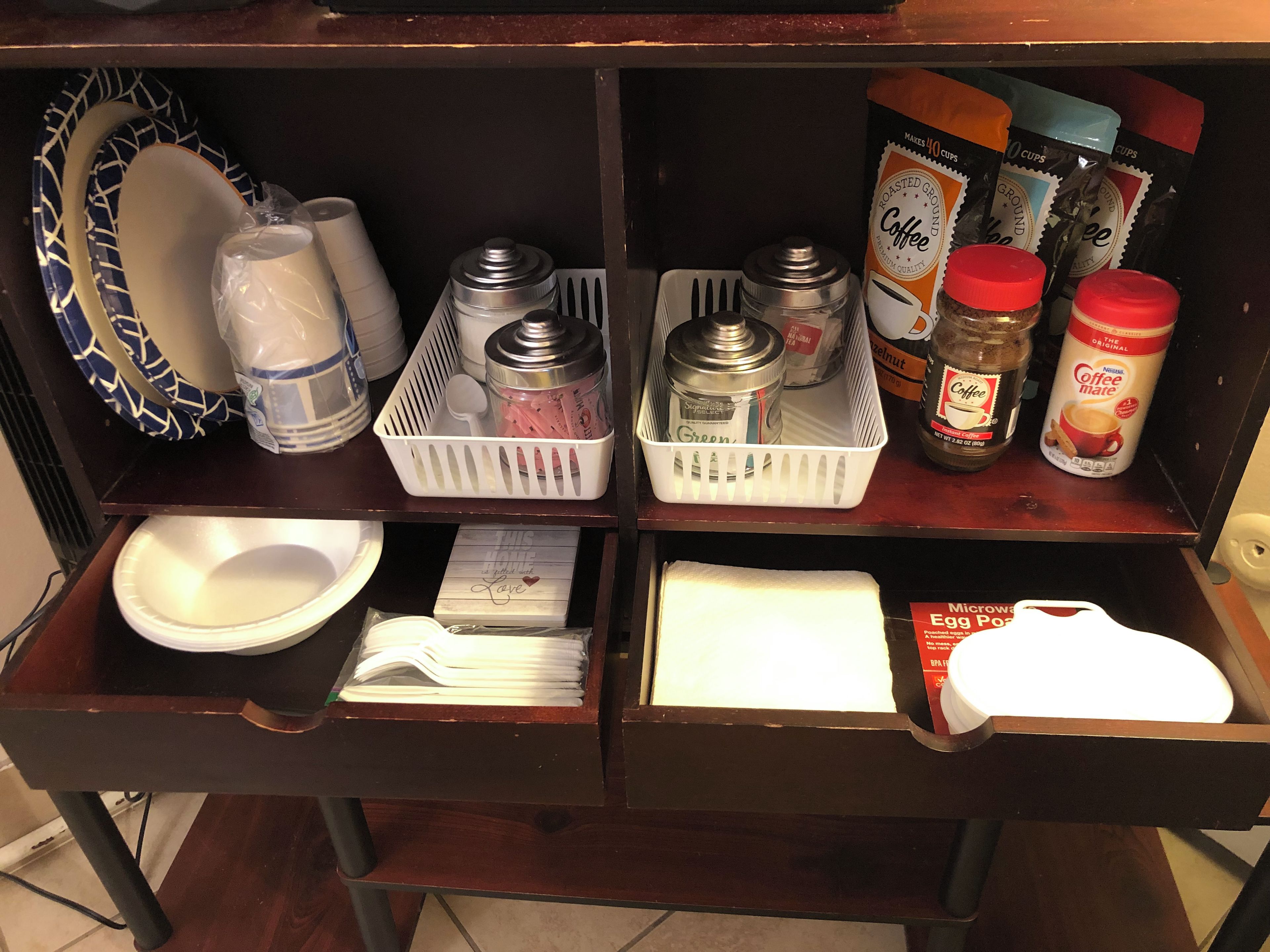 Una encimera de cocina con diferentes objetos, como una cafetera, frascos y un microondas.