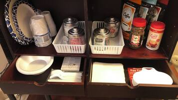 Una encimera de cocina con diferentes objetos, como una cafetera, frascos y un microondas.