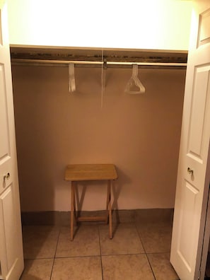 Pieni puinen penkki vaatekaapissa, jonka yläpuolella on vaatetanko.