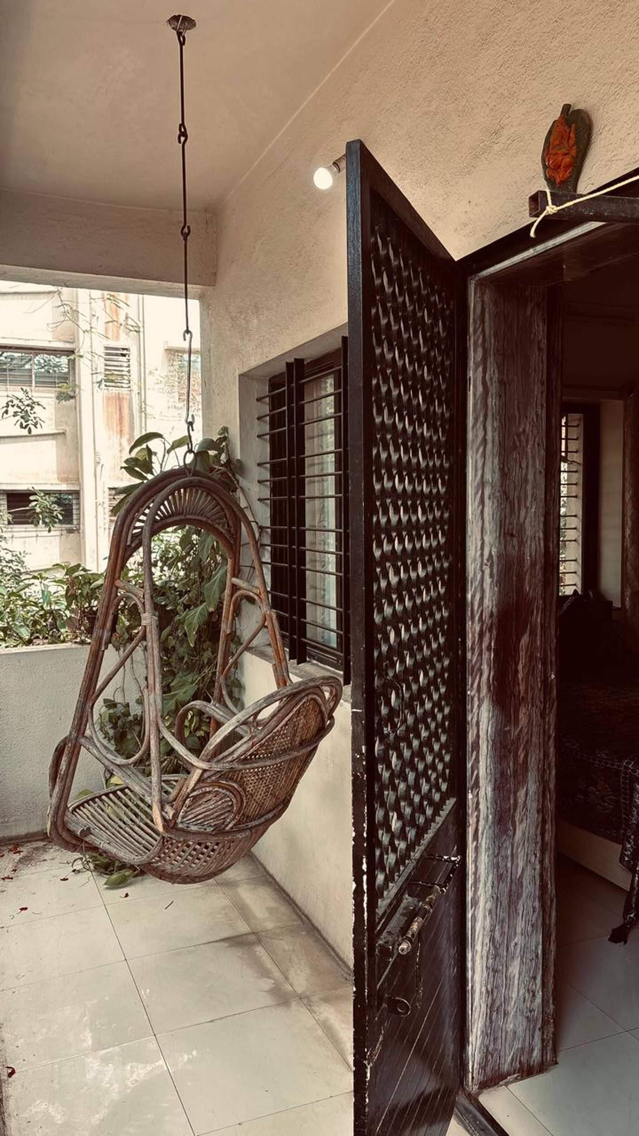 A room with a wicker chair, a black door, and a hanging light fixture.
