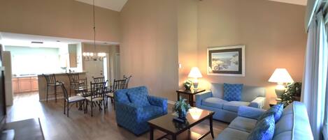 Amplia sala de estar con comedor, ventilador de techo y cocina al fondo.