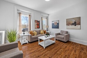 Ein modernes Wohnzimmer mit einer Couch, Sesseln, einem Couchtisch und Kunstwerken an den Wänden.