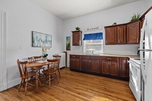 Eine Küche mit Holzschränken, einem weißen Kühlschrank und einem Esstisch mit Stühlen.