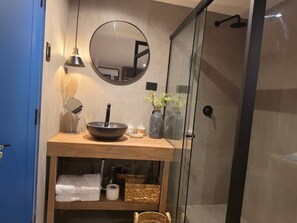 A modern bathroom with a round mirror, a bowl sink, and a glass shower enclosure. - New Listing (Cusco)