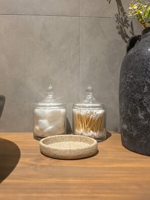 Two glass jars with lids, one containing cotton swabs and the other a white substance, on a wooden surface with a textured bowl in front. - New Listing (Cusco)