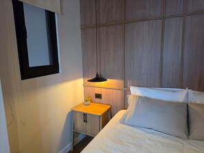 Habitació d'hotel amb llit, taulell, làmpada i mirall.