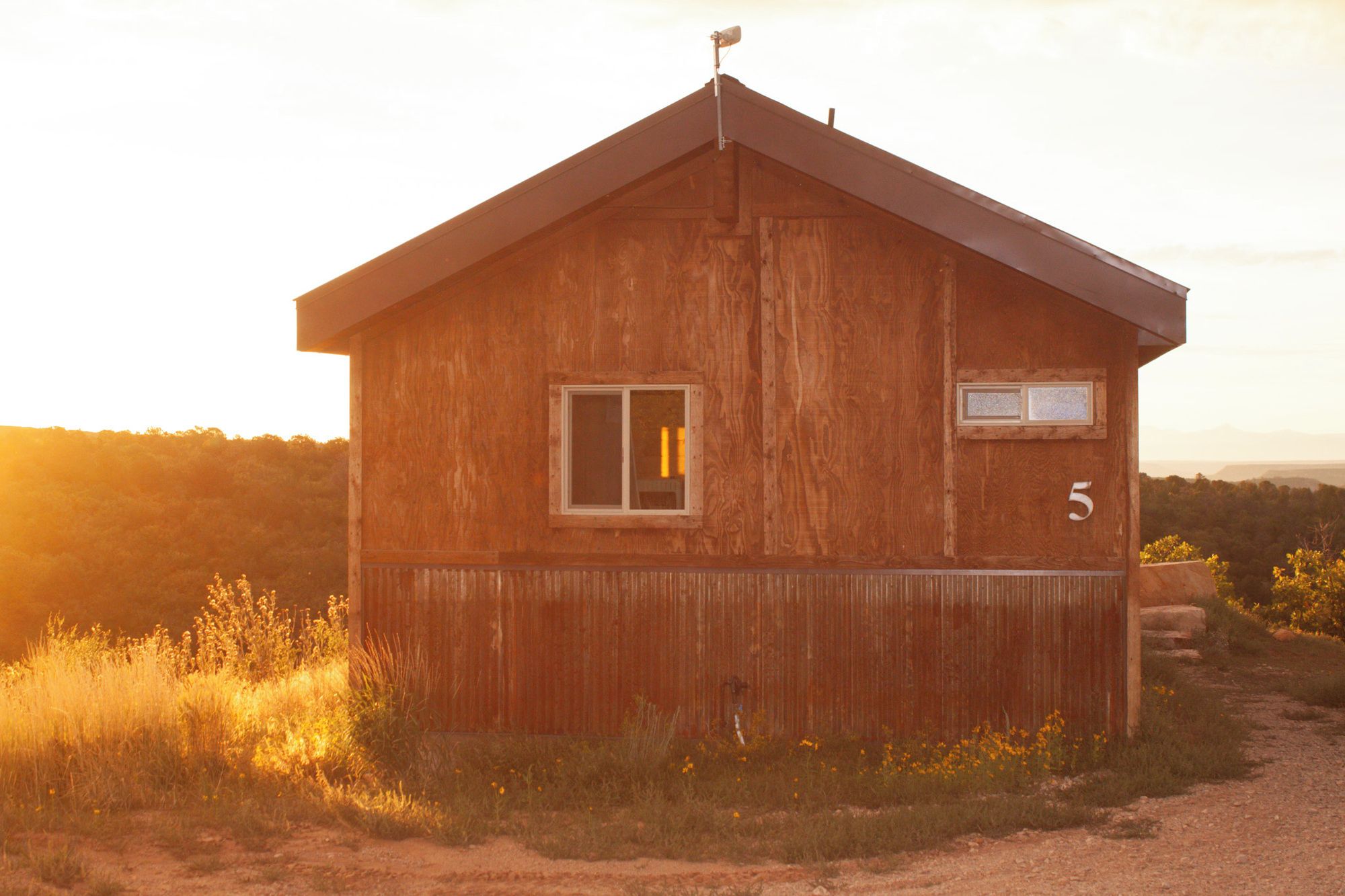 A rustic wooden cabin with a gabled roof, a small window, and a number '5' sign on the side.