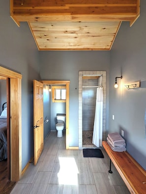 Ein Holzinnenraum mit Dusche, Toilette und einer Sitzbank mit Handtüchern.