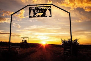 Skilt for Wolf Springs Ranch med solnedgang i baggrunden.