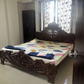 A bedroom with a wooden bed, a wardrobe, and a window with curtains.