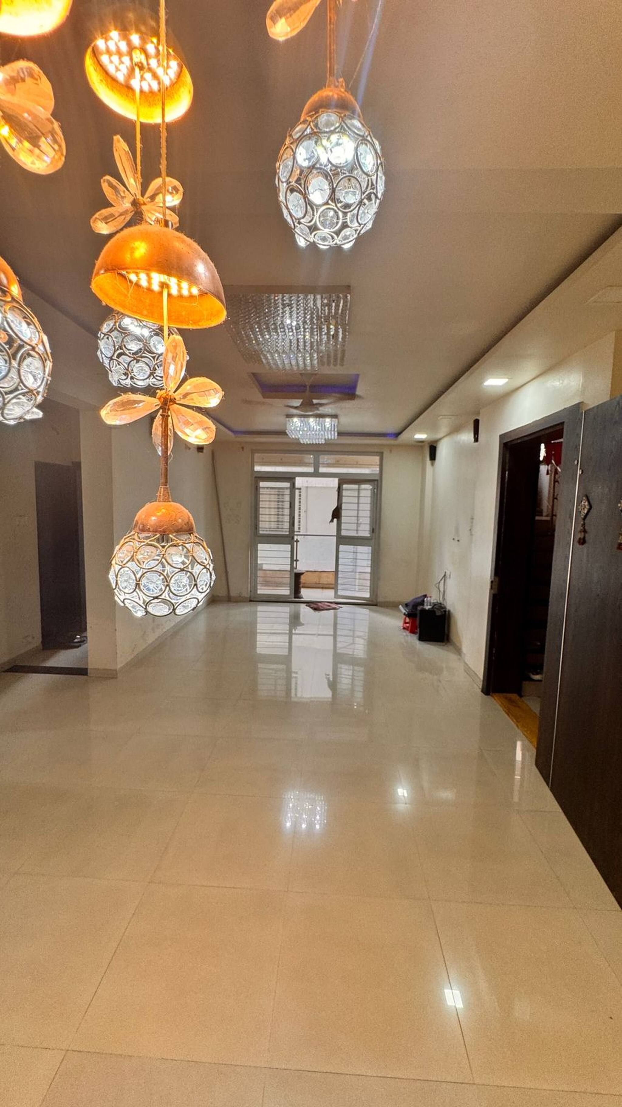 A spacious hallway with multiple hanging light fixtures and a large door at the end.