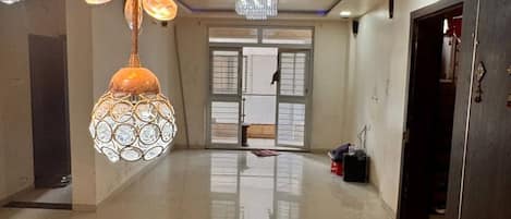 A spacious hallway with multiple hanging light fixtures and a large door at the end.