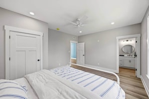 A bedroom with a bed, a ceiling fan, and a bathroom with a mirror and sink. - Nolin Lake House | Sleeps 10 | Golf Cart | Clubhouse (Grayson County)