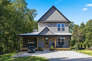 A two-story house with a covered porch, a car parked in front, and a gravel driveway. - Nolin Lake House | Sleeps 10 | Golf Cart | Clubhouse (Grayson County)