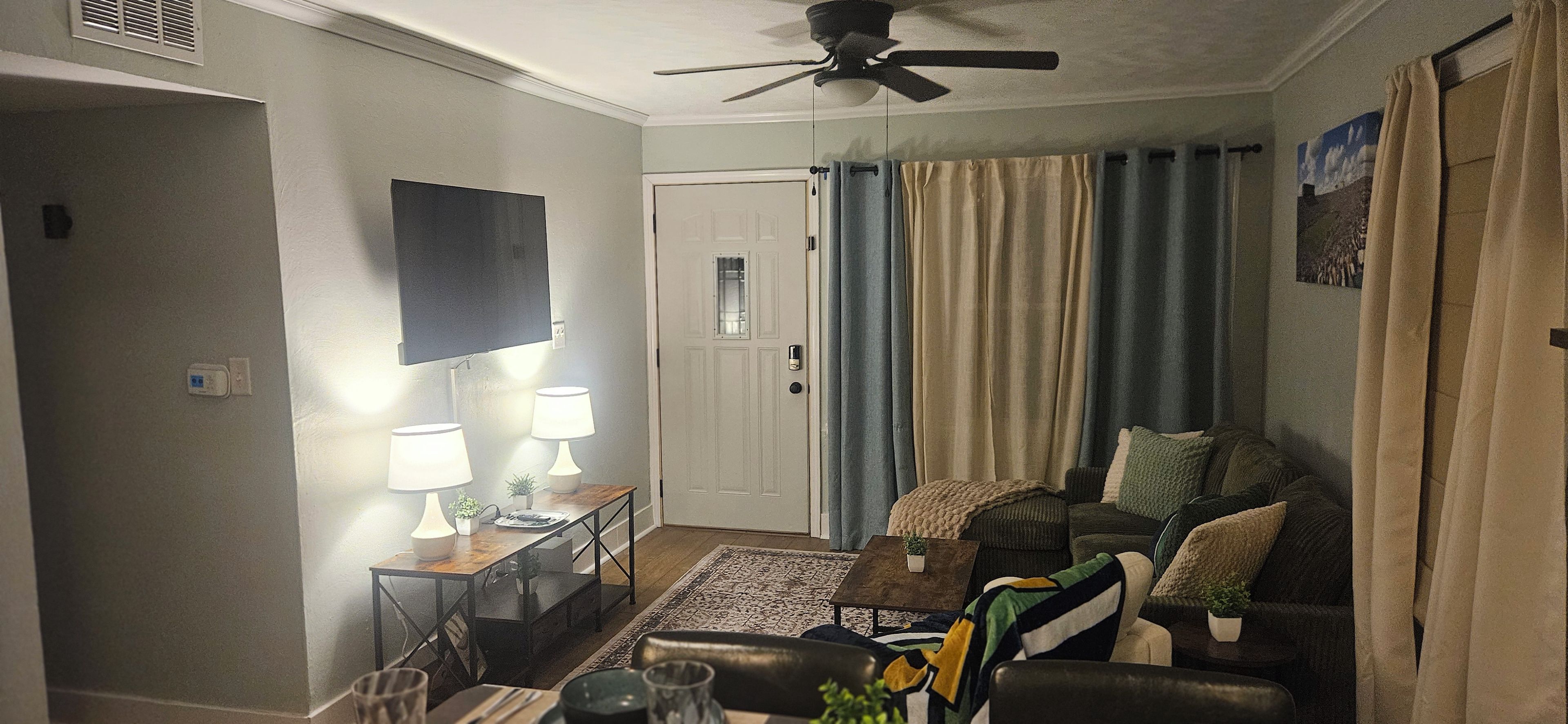 A living room with a sofa, coffee table, and a television mounted on the wall.
