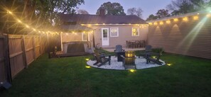 A backyard with a patio area, outdoor furniture, and string lights. - Notre Dame Retreat I Hot Tub, Fire Pit & EV Charger (South Bend)
