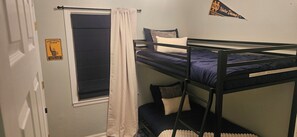 Ein Schlafsaalzimmer mit Etagenbetten, einem Fenster mit Vorhängen und einer Tür mit einem Schild.