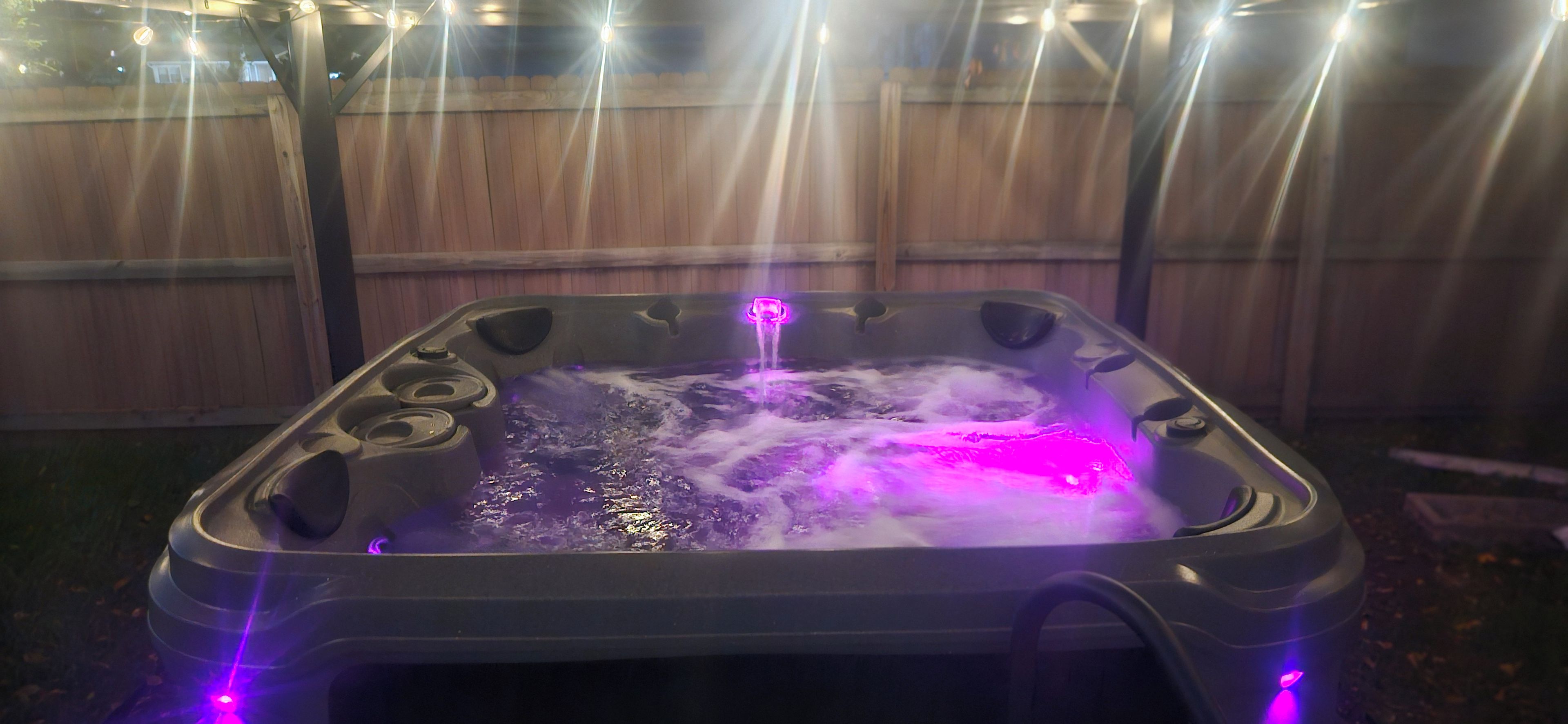 Un jacuzzi con una valla de madera al fondo.