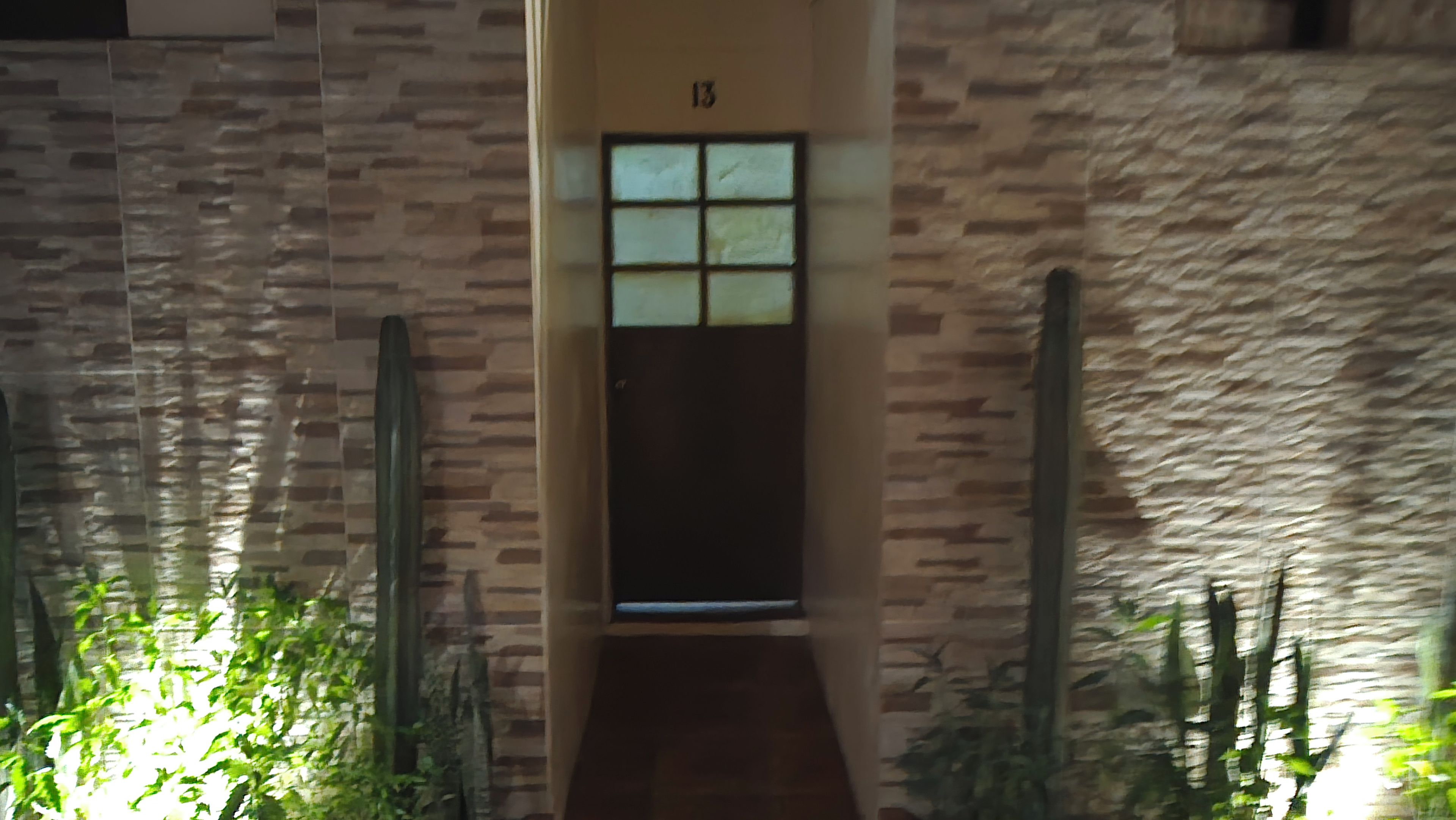 Un pasillo con una puerta marcada con el número 13 y una ventana encima.