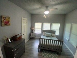 A bedroom with a crib, a dresser, a lamp, and a painting on the wall. - Historic and Charming in the Heart of Town (Fort Worth)