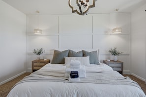Een moderne slaapkamer met een groot bed, twee nachtkastjes en een decoratieve plafondlamp.