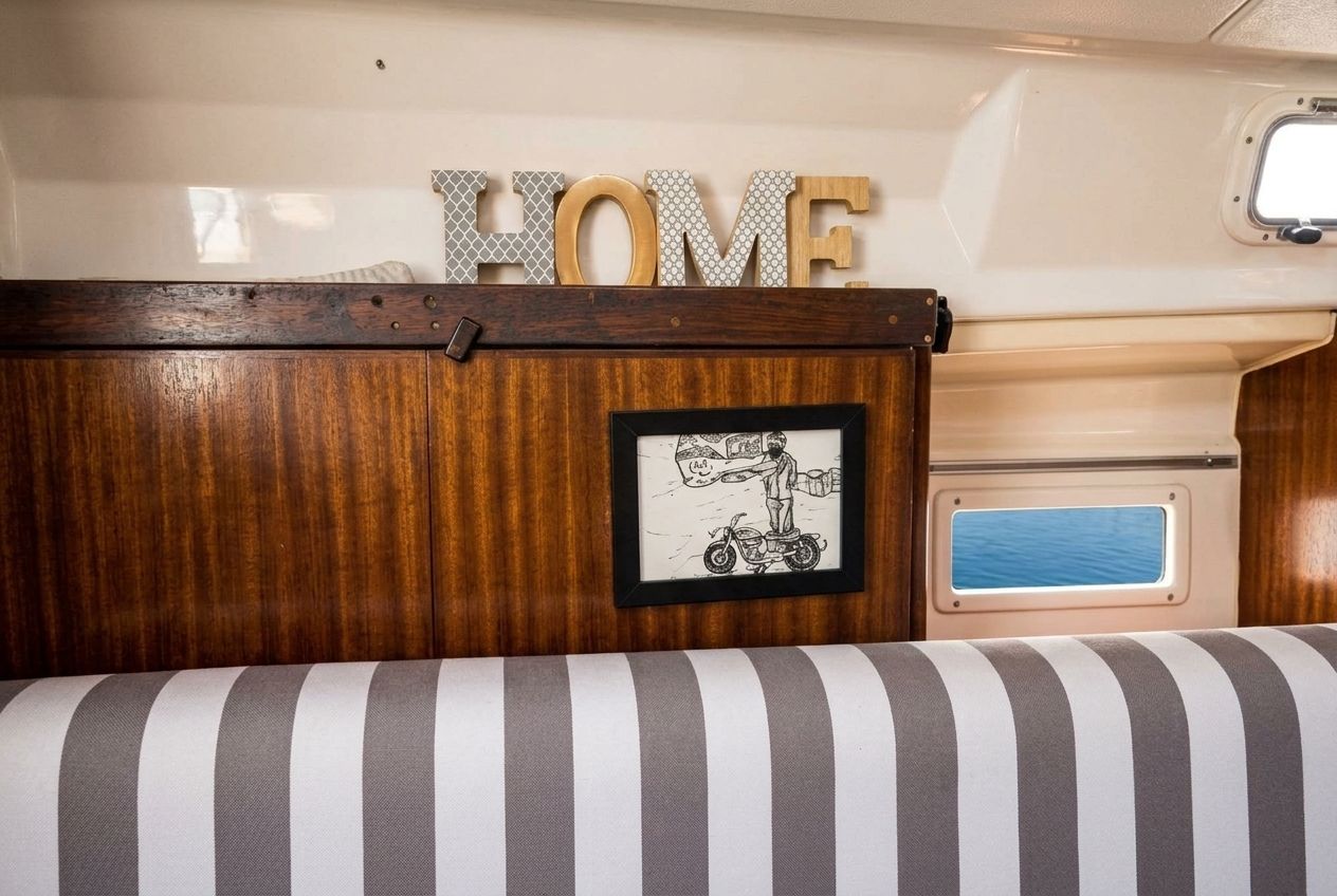 Un espacio interior acogedor con un mueble de madera, un cuadro enmarco con una persona en motocicleta, y la palabra 'HOME' encima.
