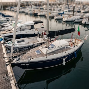 Un velero amarrado en un puerto deportivo, con otros barcos al fondo.