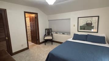 Un dormitorio con cama, una silla, una ventana con persianas y un ventilador de techo.