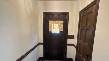 Un pasillo con suelo de mosaico, una puerta de madera oscura y un candelabro.