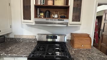 A kitchen with a gas stove, a built-in oven, and a wooden cabinet with glass doors above the stove.