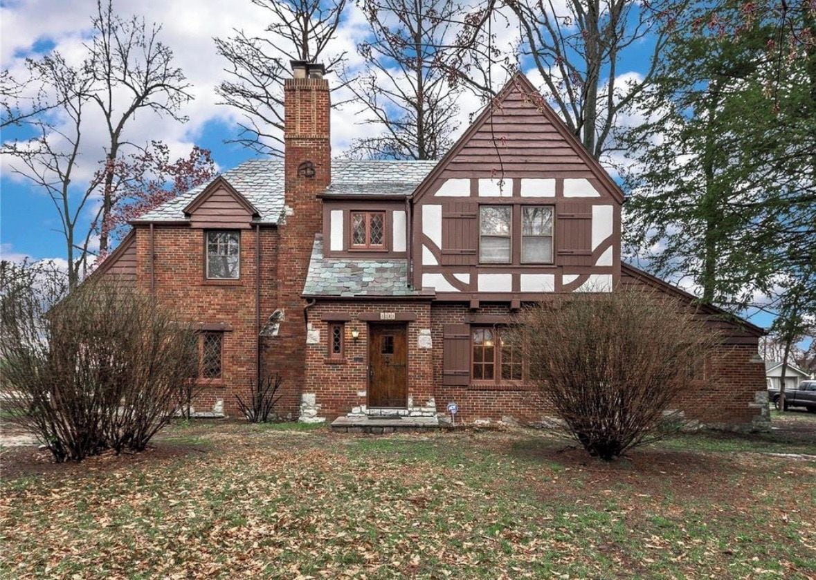 A two-story house with a brick exterior, a chimney, and a front porch.